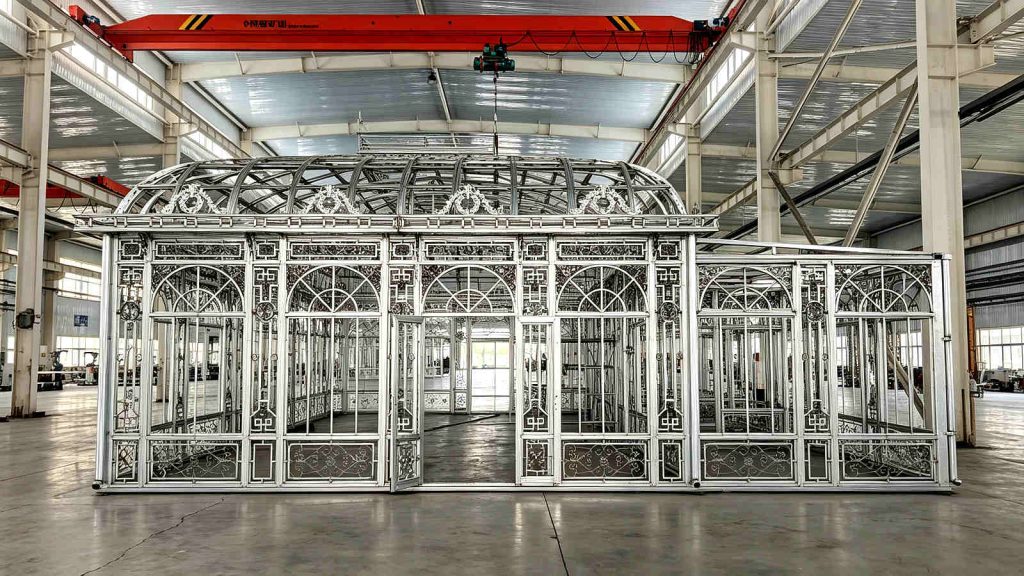Wide front view of the large Victorian greenhouse framework with open double doors during the customer's factory inspection.